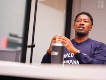 UM alum and Disney employee sitting behind a table speaking, with a water bottle in the foreground.